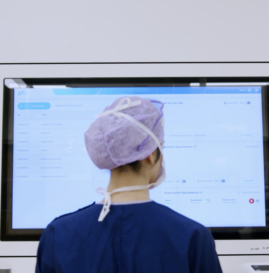 Zorgprofessional gebruikt een digitaal systeem op een touchscreen in een ziekenhuisomgeving.